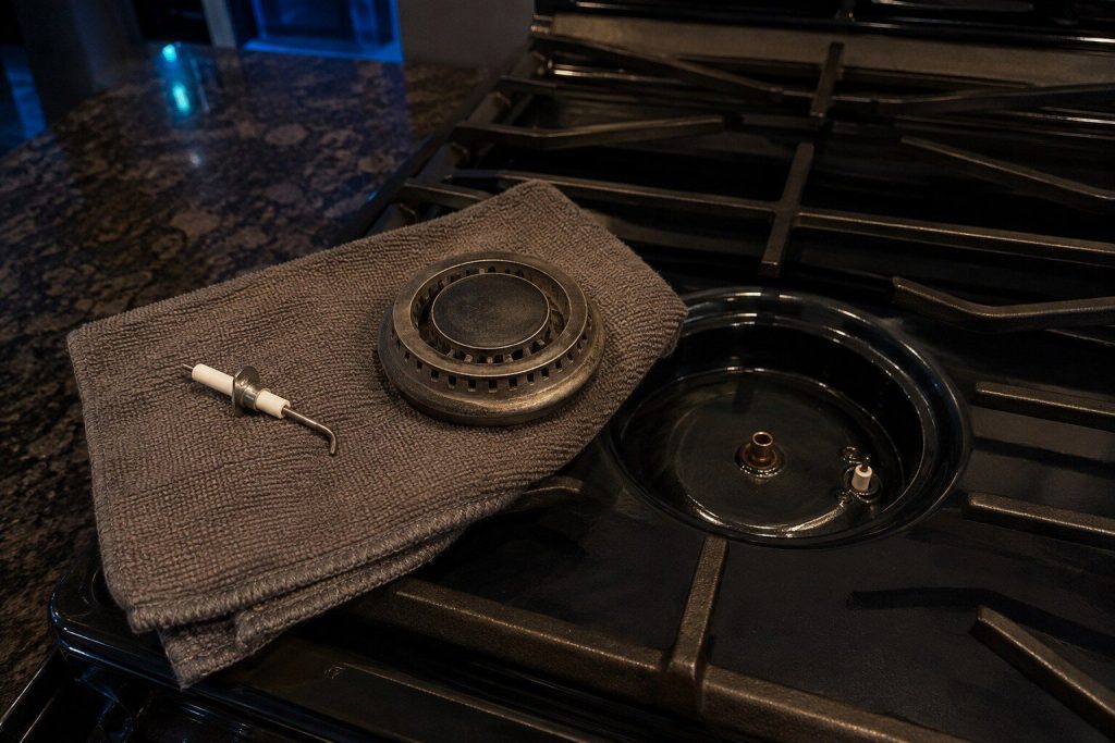 A burner head and cap apart on the hob with the igniter electrode exposed beside them